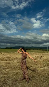 Vestido largo de fiesta con estampado animal print en tonos marrones. Presenta un diseño con breteles trenzados que se cruzan y envuelven el cuerpo, con una caída fluida y elegante.