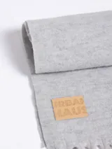 Bufanda de tejido suave en color rosado, con diseño liso y terminaciones con flecos en los extremos. Incluye una etiqueta de cuero sintético con el logo de la marca en uno de los bordes.