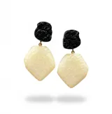 Aros colgantes compuestos por un cabezal negro con textura irregular y una pieza colgante geométrica de color beige con acabado martillado.
