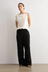 Pantalón de corte recto y tiro medio, confeccionado en tejido negro de textura sutil. Presenta un diseño minimalista con cierre frontal oculto y caída fluida.