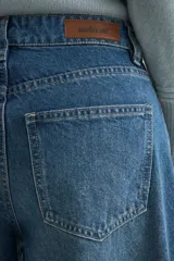 Jean de corte wide leg con diseño de costuras verticales decorativas en el frente, tiro medio y cierre frontal con botón y cremallera.