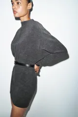 Vestido corto de tejido suave color gris oscuro, con cuello redondo y manga larga. Incluye un cinturón fino de efecto piel con hebilla metálica dorada.