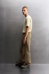 Pantalón técnico de corte regular fit en color marrón, confeccionado en tejido elástico y compacto. Cuenta con cintura ajustable con cordón interior, bolsillos frontales, bolsillo trasero con cierre oculto y bolsillo lateral con cierre en la pernera. El bajo es ajustable mediante botones a presión.