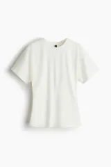 Remera de punto de algodón color blanco, con cuello redondo fino ribeteado, mangas cortas y una costura vertical central.