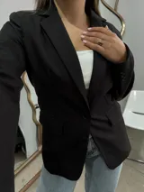 Blazer sastrero de corte clásico en color negro, con solapas de muesca, cierre frontal de un botón y bolsillos laterales con solapa.