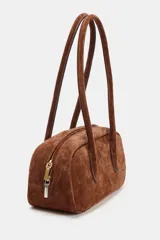 Bolso de hombro de formato alargado confeccionado en gamuza color marrón. Cuenta con doble asa de hombro y cierre superior mediante cremallera metálica.