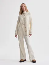 Cárdigan largo color crema, confeccionado en tejido de punto acanalado de viscosa. Tiene corte relajado, cierre frontal con botones y bolsillos de parche.