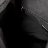 Mochila negra de poliéster con solapa y sujetador. Tiene un compartimento principal, dos bolsillos externos con cierre, un bolsillo interno con cierre y dos bolsillos internos abiertos. Las correas son regulables y los herrajes son plateados.