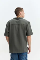 Camisa de manga corta color beige con tejido calado de líneas verticales y cuello abierto estilo resort.