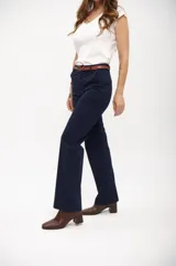 Pantalón de vestir ancho color azul marino, de tiro alto y corte recto, con pliegues frontales y cinturón marrón.