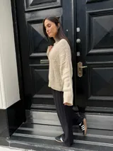 Sweater color crema con cuello alto y diseño de trenzas.