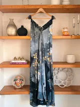 Vestido largo sin mangas con escote en V pronunciado, de corte amplio y fluido, con estampado abstracto en tonos rosados, marrones y blancos, y un cordón trenzado ajustable en la cintura.