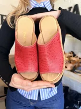 Zuecos de plataforma corrida color rojo con textura símil cocodrilo y suela de madera clara.