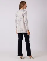 Cárdigan de punto marca Sioni, color beige con estampado floral en tonos azules. Presenta escote redondo a la base, cierre frontal con un botón metálico y mangas largas de corte recto.