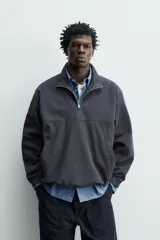 Sobrecamisa de corte regular confeccionada en mezcla de algodón y lyocell, con cuello alto y cierre frontal de cremallera. Presenta mangas largas con puños elásticos, bolsillos laterales de vivo y bajo ajustable con elástico en los laterales.