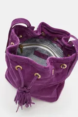 Mini bandolera de piel color morado, de diseño tipo saco con cierre fruncido y cordón ajustable con borlas en el extremo. Cuenta con asa larga ajustable y detalles metálicos dorados.
