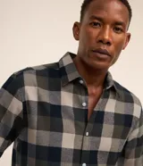 Camisa de franela para hombre, modelo comfort, con estampado de cuadros en tonos azules, blancos y negros, cuello camisero, manga larga y cierre frontal de botones.
