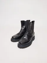 Bota tipo Chelsea de cuero con textura de reptil, color suela, con paneles elásticos laterales negros y suela de goma dentada con pespuntes en contraste.