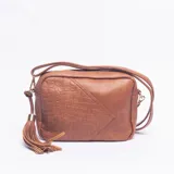 Bandolera de tamaño mediano color marrón, con diseño combinado de textura lisa y efecto croco en uno de sus laterales. Cuenta con correa larga ajustable, cierre superior y detalle de borla decorativa en uno de los costados.