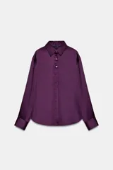 Camisa de cuello solapa y manga larga acabada en puño ancho, confeccionada en tejido satinado de color violeta. Cuenta con cierre frontal mediante botones dorados.