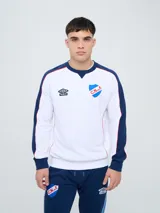 Buzo deportivo azul marino con detalles en rojo y blanco en cuello, hombros y mangas, de cuello redondo y manga larga, con el logo de Umbro y el escudo del Club Nacional de Football bordados en el pecho.