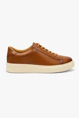 Championes urbanos de cuero color marrón, con diseño minimalista, cordones al tono y suela de goma blanca.