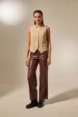 Chaleco sin mangas confeccionado en suede, con escote en V, cierre frontal con botones metálicos y bolsillos laterales.