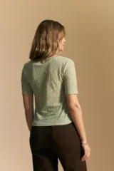 Top de manga corta confeccionado en tejido jacquard con textura en relieve. Presenta escote en V y un diseño frontal con líneas diagonales que crean un efecto cruzado.