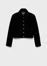 Chaqueta corta de piel bovina serraje color negro, con cuello camisero, bolsillos de parche con solapa en el frente, manga larga y cierre frontal de botones.