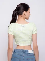 Crop top de punto color verde claro con estampado a cuadros blancos, escote redondo y mangas cortas.