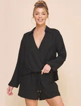 Blusa Allie Rose de color negro, corte holgado con escote en V cruzado y cuello camisero. Presenta mangas largas amplias con puños sutilmente fruncidos y diseño de silueta fluida.