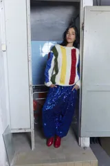 Sweater tejido a mano en lana merino con diseño a rayas verticales de colores sobre fondo crudo, cuello redondo y calce holgado.