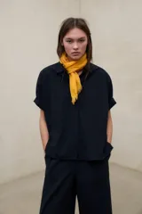 Camisa negra de manga corta con tejido de textura seersucker, corte oversize, cuello camisero y cierre frontal con botones.