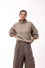 Sweater de punto grueso con cuello alto, diseño de hombros caídos y mangas amplias con puños acanalados.