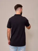 Remera polo negra de piqué de algodón con cuello clásico y tapeta de dos botones. Presenta un pequeño logo bordado en el pecho.