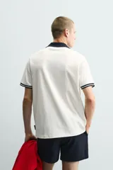 Polo de corte relajado confeccionado en piqué de algodón color blanco. Presenta cuello solapa en color negro con abertura frontal, mangas cortas con ribetes a contraste y estampado conmemorativo USA 94 FIFA World Cup.