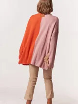 Buzo tejido oversized con bloques de color blanco y gris, cuello redondo en verde neón, tajos laterales y flecos verdes en las mangas.