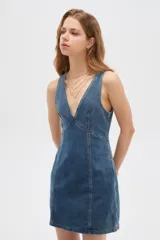 Vestido mini de jean al cuerpo, con escote en V profundo y costuras pespunteadas visibles.