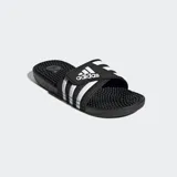 Ojotas Adidas Adissage negras con tres franjas blancas en la tira superior ajustable con velcro. La plantilla cuenta con protuberancias de masaje EVA.