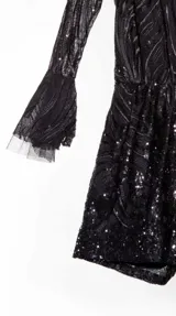 Mono corto de fiesta color rosado con lentejuelas, mangas largas acampanadas y escote redondo.