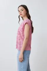 Blusa de algodón color rosa pastel con frente de tela broderie, cuello redondo y mangas cortas con terminación al corte.