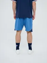 Bermuda deportiva Umbro del Club Nacional de Football, modelo Nexo para hombre, en color azul marino con detalles en rojo y blanco. Cuenta con el escudo del club bordado en la pierna derecha y el logo de Umbro en la izquierda, además de cordón ajustable en la cintura.