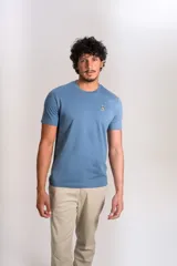 Remera de cuello redondo y manga corta en color azul, con un pequeño bordado de un pingüino esquiador en el pecho.