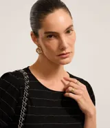Blusa de manga corta color negro con líneas horizontales metalizadas plateadas, cuello redondo y botones decorativos dorados en las mangas.