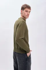 Sweater de punto color verde oliva, con cuello redondo y mangas largas. Diseño clásico con terminaciones acanaladas en cuello, puños y ruedo.