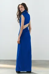 Vestido largo color azul, confeccionado en tejido elástico, con cuello alto, manga muy corta y detalle de lazada en la cintura. Cuenta con abertura en la espalda.
