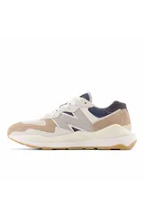 Championes urbanos New Balance modelo 57/40, con diseño de paneles en tonos beige, blanco y azul marino. Presentan una entresuela gruesa y suela de goma color caramelo.