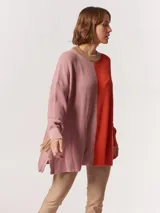 Buzo tejido oversized con bloques de color blanco y gris, cuello redondo en verde neón, tajos laterales y flecos verdes en las mangas.