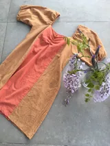 Vestido corto de algodón en calidad tusor con diseño en bloque de color, combinando un panel central coral con laterales y mangas abullonadas en color tostado. Presenta escote cuadrado con frunce en el centro del busto.