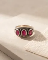 Anillo de plata envejecida con tres piedras naturales de rubí en corte ovalado en disposición vertical, con detalles grabados en el metal.